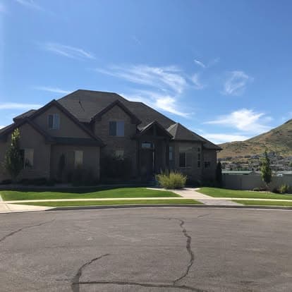Modern suburban home with landscaped yard and mountain view under blue sky.