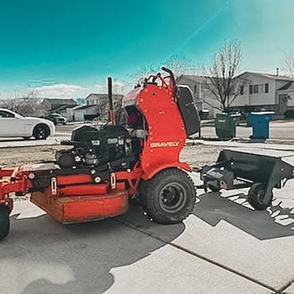 Gravely lawn care equipment with a trailer attachment parked in a residential area.