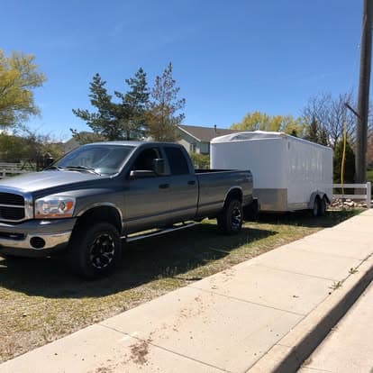 Silver pickup truck parked next to a white trailer on a sunny day.