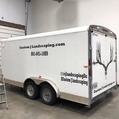 Custom landscaping trailer with deer antler design and contact information.