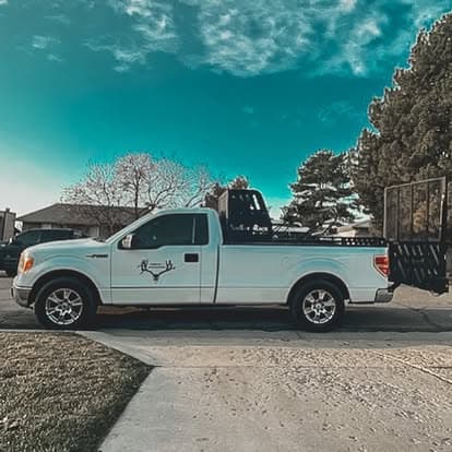 White pickup truck with a flatbed parked on a driveway under a clear blue sky.